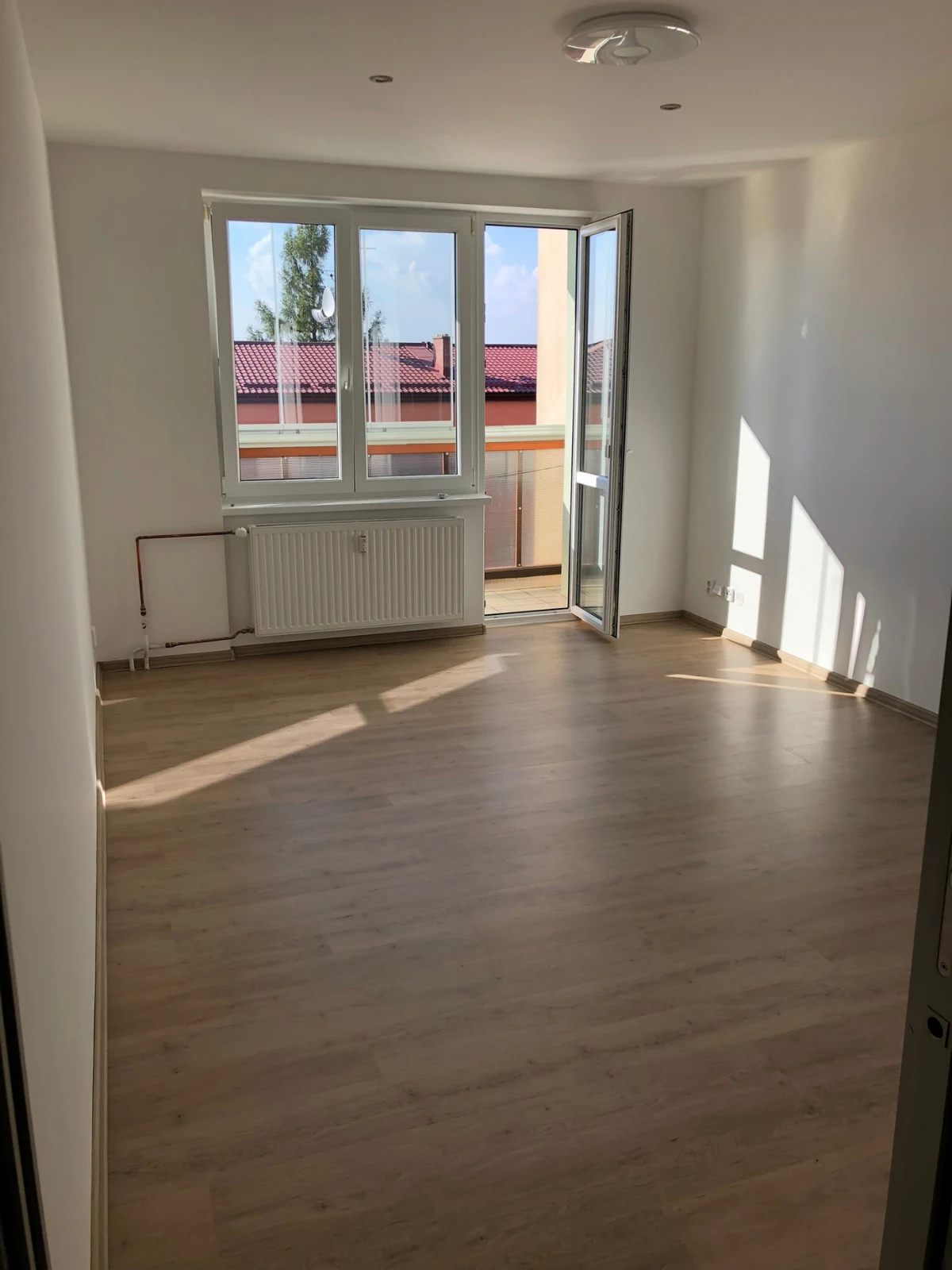 Světlá ložnice s velkým oknem a vstupem na balkon